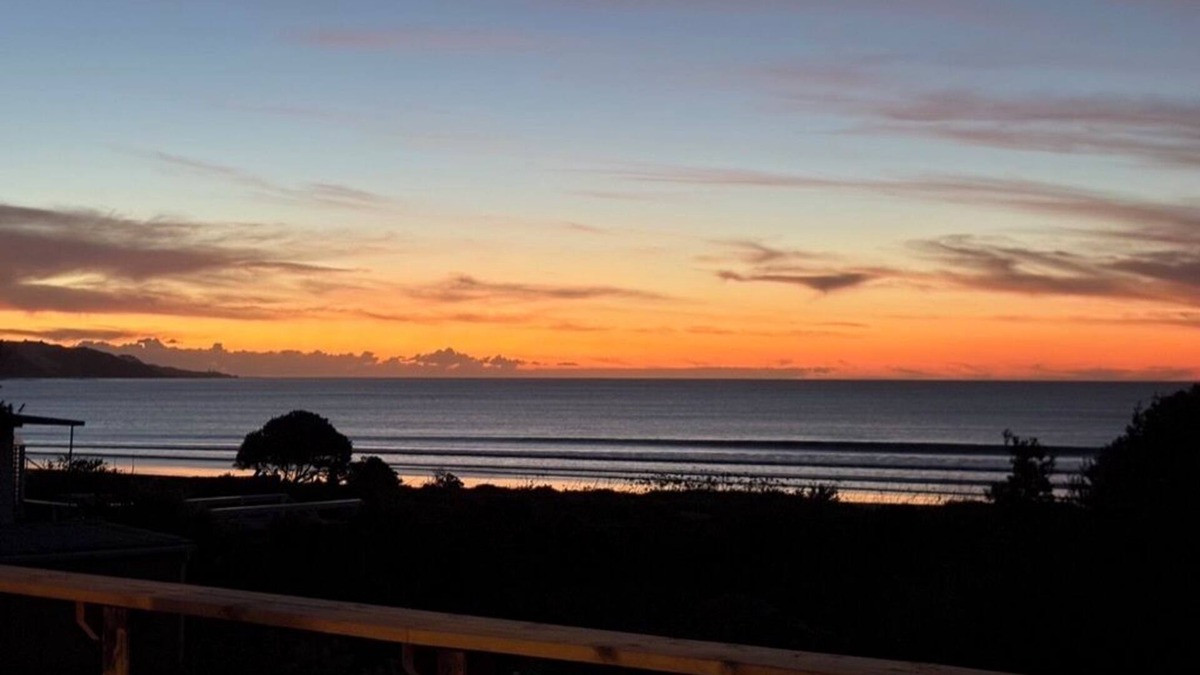 Ahipara House | Watch the waves from the large, sunny deck of this 1950's bach. Pet friendly.