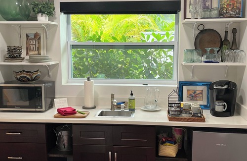 Parrot Cove Cottage | Chill on the patio overlooking the pool & lush gardens & grill your dinner!