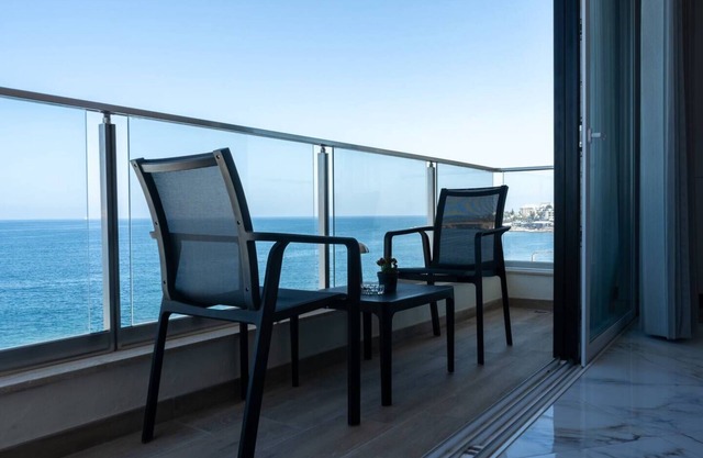 Seafront Bugibba apartment with balcony and stunning 180° views. Bright, beach-style interiors, lift access, and steps from dining and the shoreline.